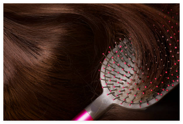Close-up of brown hair being brushed with a pink-tipped detangling brush