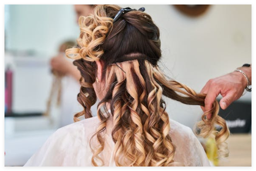 Hair stylist installing halo hair extensions on a client for a natural blended look